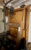Full view showing wooden rack, five pipe clamps at top, bar clamps resting, extra lumber below