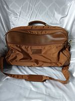 Front view of brown/tan Europa weekender bag showing exterior pocket, logo patch, shoulder strap