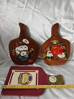 Group shot showing two wooden hand-painted boards and one ceramic red board with ruler for scale