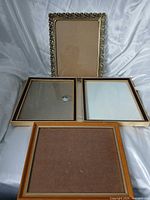 Four picture frames laid flat showing relative sizes, colors, glazing present or missing