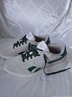 Side view of both sneakers showing suede uppers, green accents and overall condition