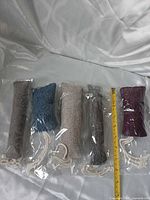 Five packaged woven fabric cat toys beside ruler