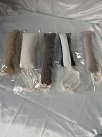 Five sealed fabric tube cat toys with rope cords displayed on surface