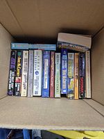 Box containing 18 mass market paperbacks showing spines