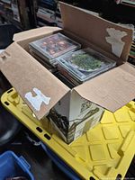 Open cardboard box filled with stacked audio CDs