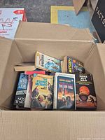 Open cardboard box showing assortment of vintage sci-fi paperbacks on top layer