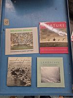 All four photobooks laid out on blue surface showing covers