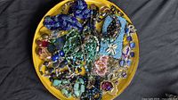 full view of assorted jewelry spread on yellow plate