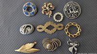 All ten brooches arranged on textured background