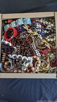 Box filled with assorted costume jewelry pieces