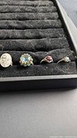 Four rings including oval clear cluster, aqua blue stone, red stone, small clear stone