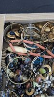 Top view of box showing mixed metal bangles, hoop earrings, bead strands and loose pieces