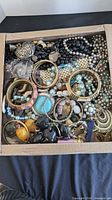 Box filled with assorted bracelets, necklaces, beads and pendants