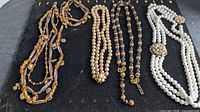 Four necklaces laid out showing overall styles and strand counts