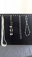 Overview of all four pearl necklaces hanging on display board
