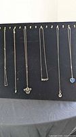 Six necklaces hanging on display board