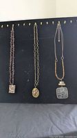Three necklaces displayed side by side on black board