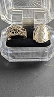 Both silver rings in display case, showing designs