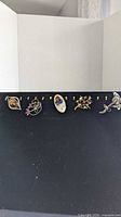 Five brooches arranged in a row on display board