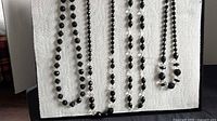 All five black and clear glass bead necklaces displayed vertically