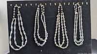 Four multi-strand crystal necklaces hanging on display board