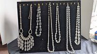 Display board showing six necklaces in lot