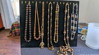 Full view of nine amber glass bead necklaces on display board
