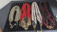 All four multi-strand bead necklaces laid out side by side