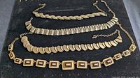 Four gold-tone vintage necklaces on display board