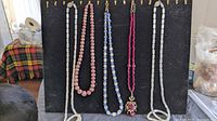 Five necklaces displayed on black board