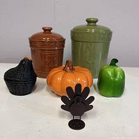 Group shot of all items: two canisters, glass pepper, ceramic pumpkin, wicker basket with lid, metal turkey