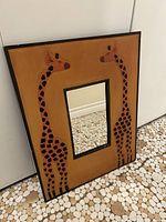 Front view of rectangular wall mirror with giraffe-decorated wooden frame