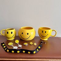 Group shot of all nine items: three ceramic vessels, lanyard, watches, pin, spinner