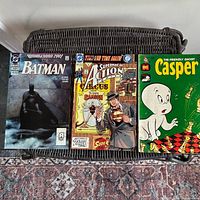 Front covers of three comic books laid side by side on wicker surface