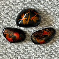 All three black lacquer river rock paperweights showing painted koi and dragonfly designs
