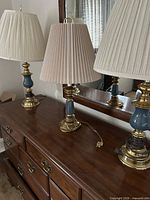 Three brass and blue ceramic lamps with shades on dresser