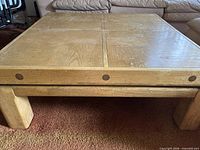 Front view of coffee table showing light oak finish, dowel accents, block legs