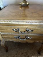 Top and drawer front of one end table showing wood grain, ornate pulls