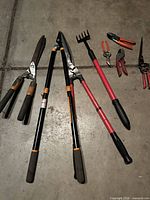 Overall view of long-handled tools and some hand tools on concrete floor