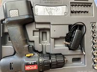 Open case showing drill, charger, driver bits and sockets