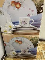 Box graphics showing dinnerware with fruit motif and blue trim