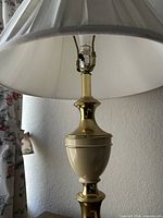 Close-up of brass and cream ceramic table lamp with pleated shade