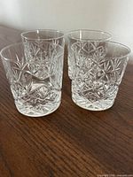 Four matching cut crystal DOF glasses on wooden surface