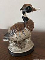 Front left profile of goose figurine on base