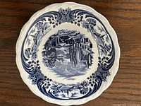 Top view of blue transferware saucer showing full landscape pattern and scalloped rim