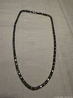Full view of silver tone braided chain necklace laid flat