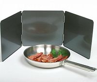 Front view of tri-fold splatter guard set up behind frying pan