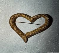 Front view of textured gold-tone open heart brooch