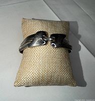 Bracelet on display pillow showing front curved end caps and chain detail