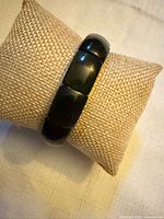 Front view showing polished black obsidian rectangular links on pillow